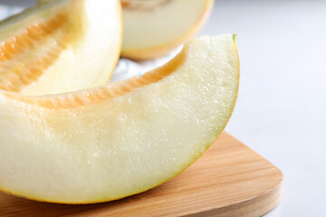 Pieces of delicious honeydew melon on wooden board, closeup