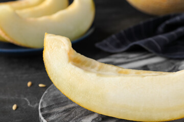 Slice of delicious honeydew melon on grey marble board, closeup