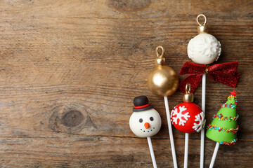 Delicious Christmas themed cake pops on wooden table, flat lay. Space for text