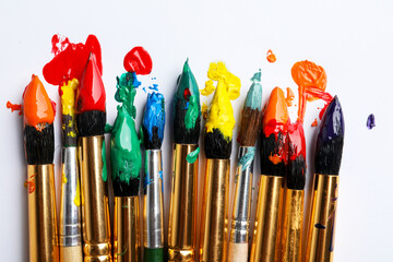Brushes with colorful paints on white background, flat lay