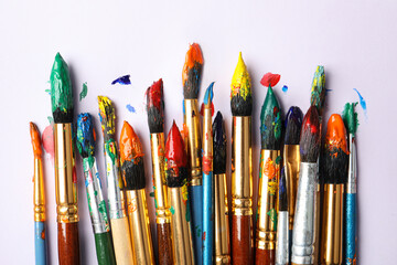 Brushes with colorful paints on white background, flat lay