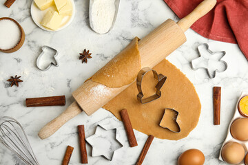 Rolling pin, dough, different cutters and ingredients for Christmas cookies on white marble table,...