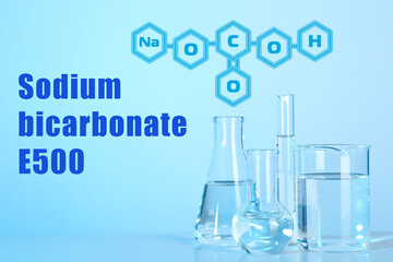 Text Sodium bicarbonate E500 with soda formula and laboratory glassware on background