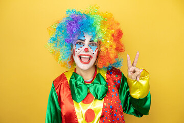 Clown standing over yellow insolated yellow background showing and pointing up with fingers number two while smiling confident and happy