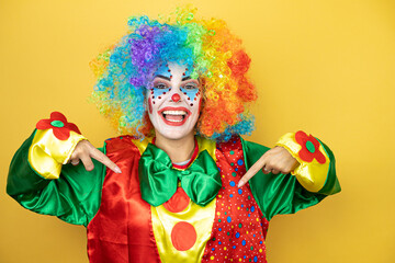 Clown standing over yellow insolated yellow background looking confident with smile on face, pointing oneself with fingers proud and happy.