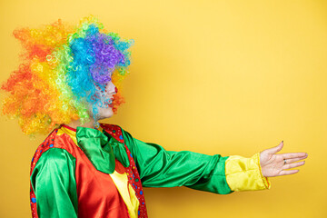 Clown standing over yellow insolated yellow background smiling friendly offering handshake as greeting and welcoming