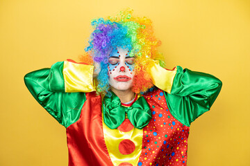 Clown standing over yellow insolated yellow background suffering from headache desperate and stressed because pain and migraine with her hands on head