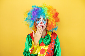 Clown standing over yellow insolated yellow background surprised covering her mouth