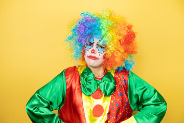 Clown standing over yellow insolated yellow background skeptic and nervous, disapproving expression...