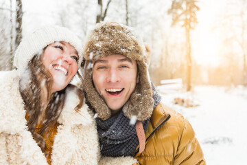 Obraz premium happy loving couple walking in snowy winter forest, spending christmas vacation together. Outdoor seasonal activities