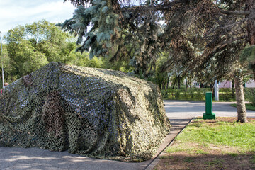 A camouflage military tent set in summer outdoors.
