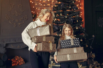 Family with cristmas gifts. Little girl near christmas tree. Beautiful mother in a white sweater.