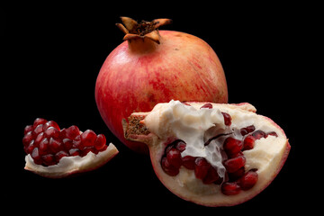 Healthy eating, antioxidants and refreshing nourishment concept open raw pomegranate isolated on black background with clipping path cutout