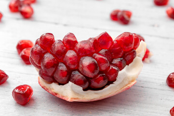 Healthy eating, antioxidants and refreshing nourishment concept open raw pomegranate isolated on white wooden background