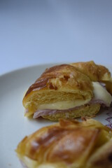 Close up of ham and cheese croissant served on white plate