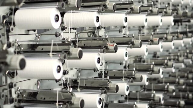 Weaving Plant For The Production Of Plastic Or Polypropylene Bags . Rows Of White Reels With Ropes Making Plastic Sacks In A Modern Production Plant