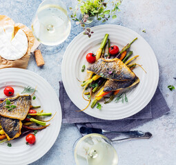  sea fish with rainbow carrot and wine     glasses on bright table. gourmet dissh