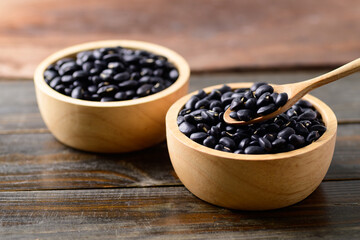 Black kidney beans in a bowl with spoon on wooden background