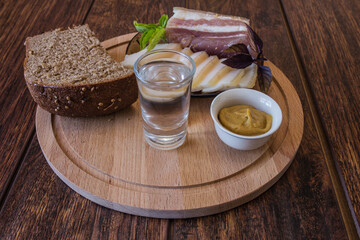 Slicing different types of lard, black bread, mustard and a glass of vodka