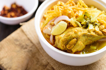 Northern Thai food (Khao Soi), Spicy curry noodles soup with chicken eating with crispy deep-fried egg noodles, pickled mustard, shallots, lime and ground chillies fried in oil