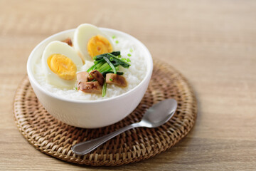 Asian food, Rice soup with boiled egg, grilled mushroom and spinach in a bowl on woven rattan sheet