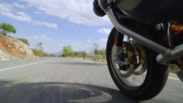 Motorcycle ridind on a road in nature. Close up wheel on a bumpy asphalt road. Recorded at 100 fps.