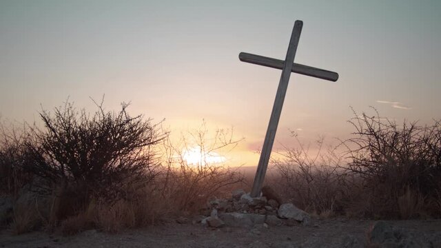Wooden crucifix inclined on a mountain, with sunset. Nailed to a set of stones.