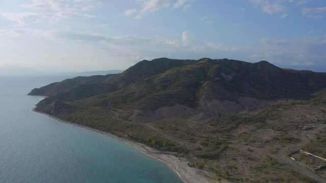 Aerial view rising towards mountains, on the coast of Mangla, sunny day, in Sabana Buey, Dominican republic, Caribbean America - high, dolly, drone shot	
