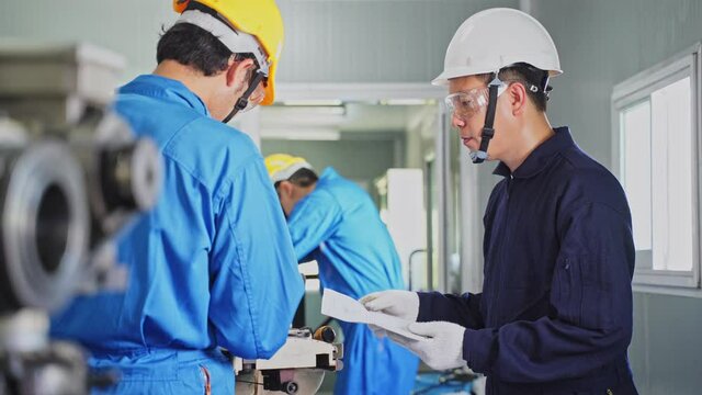 Asian engineer man training his worker for process of heavy machine.