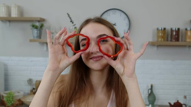 Girl vegan dancing holding fresh red slice of bell pepper on eyes. Weight loss and diet lifestyle