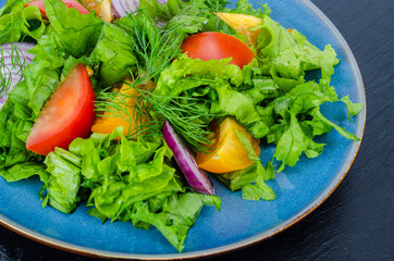 Fragment of plate with vegetables and lettuce closeup, top view