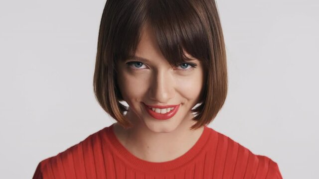 Gorgeous brunette girl with bob hair and red lips look charming smiling on camera over white background. 