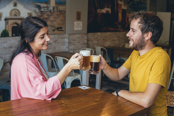 couple toasting and drinking beer in a restaurant