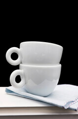 Pile of books and coffee cups on black background