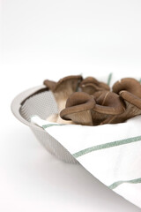Fresh mushrooms in stainless steel colander.