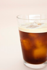 Glass of iced coffee on pink background.