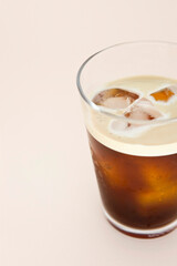 Glass of iced coffee on pink background.
