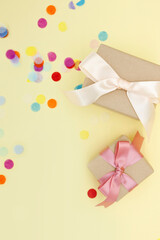Wrapped gift boxes and confetti on yellow background.
