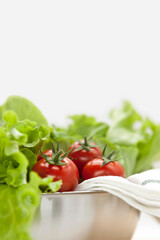 Various fresh green vegetables in stainless steel bowl.