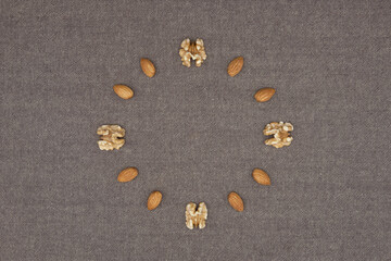 In a circle of walnuts and almonds on brown background.