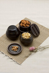Miniature pots are full of Various nuts (Pine nuts, almonds and walnuts).