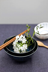 White flowers with chopsticks and spoon in bowl.