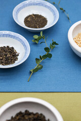 Various dried tea leaves and grains in plates.