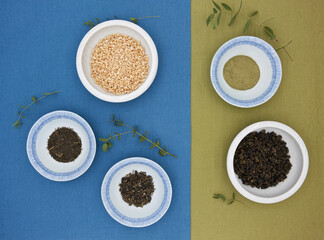 Various dried tea leaves and grains in plates.