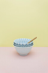 Fototapeta na wymiar Empty Bowls and wooden spoon on pastel colored background.