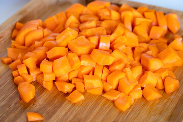 Diced carrots on wooden chopping board, food