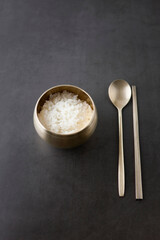 Korean rice in a brassware bowl on dark background.