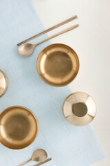 Korean traditional brassware plate setting on blue ramie cloth.