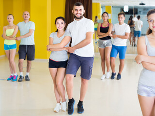 Young positive sporty girls and men learning salsa steps