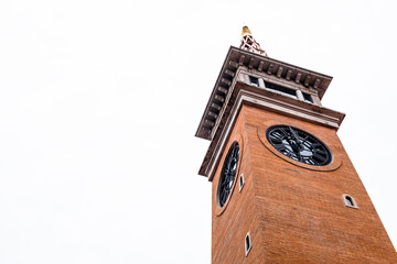 Clock tower built from orange bricks against white sky background. Low angle view of city clock tower.